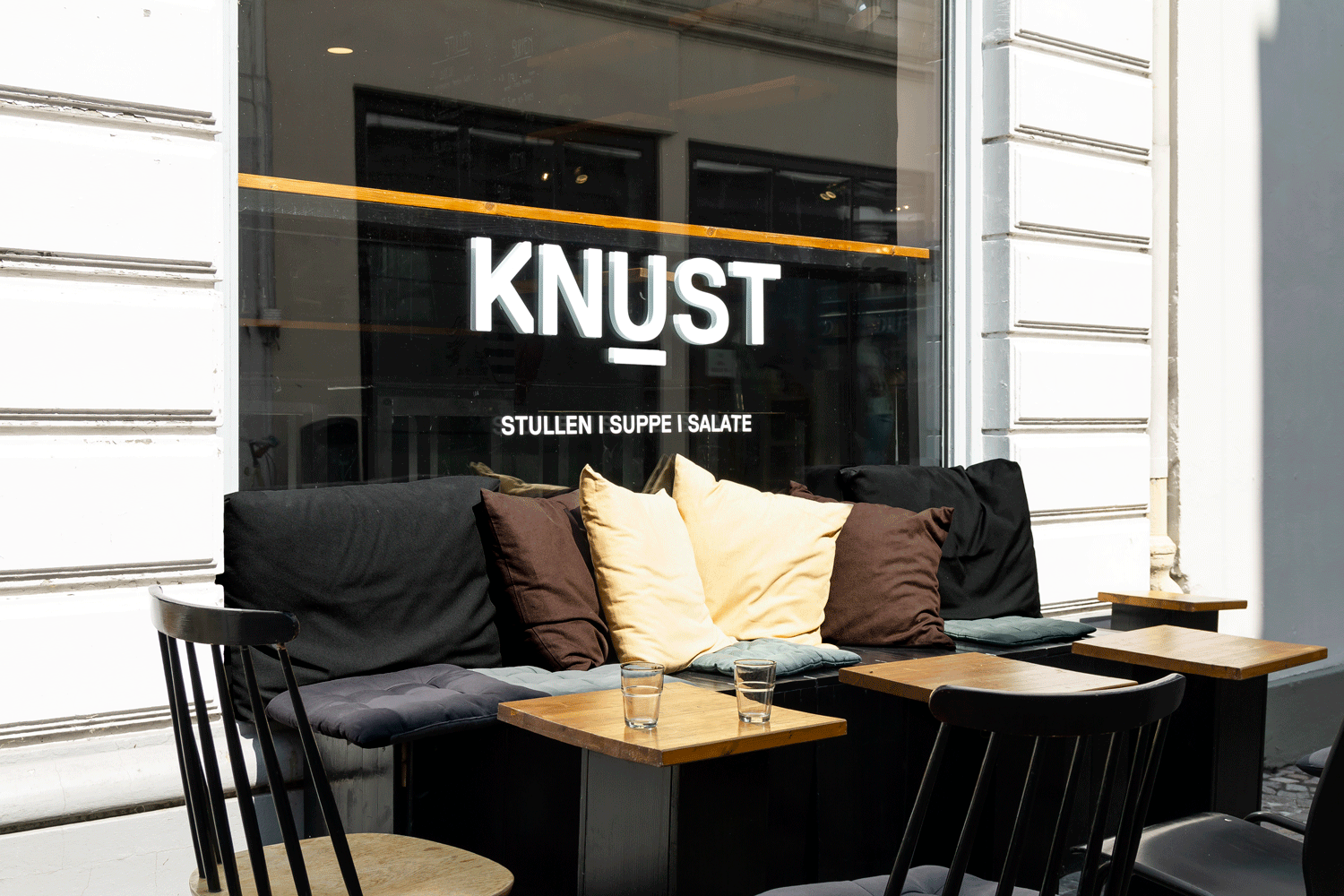 Außenaufnahme vom Ladenlokal mit Schaufenster und Sitzmöglichkeit.